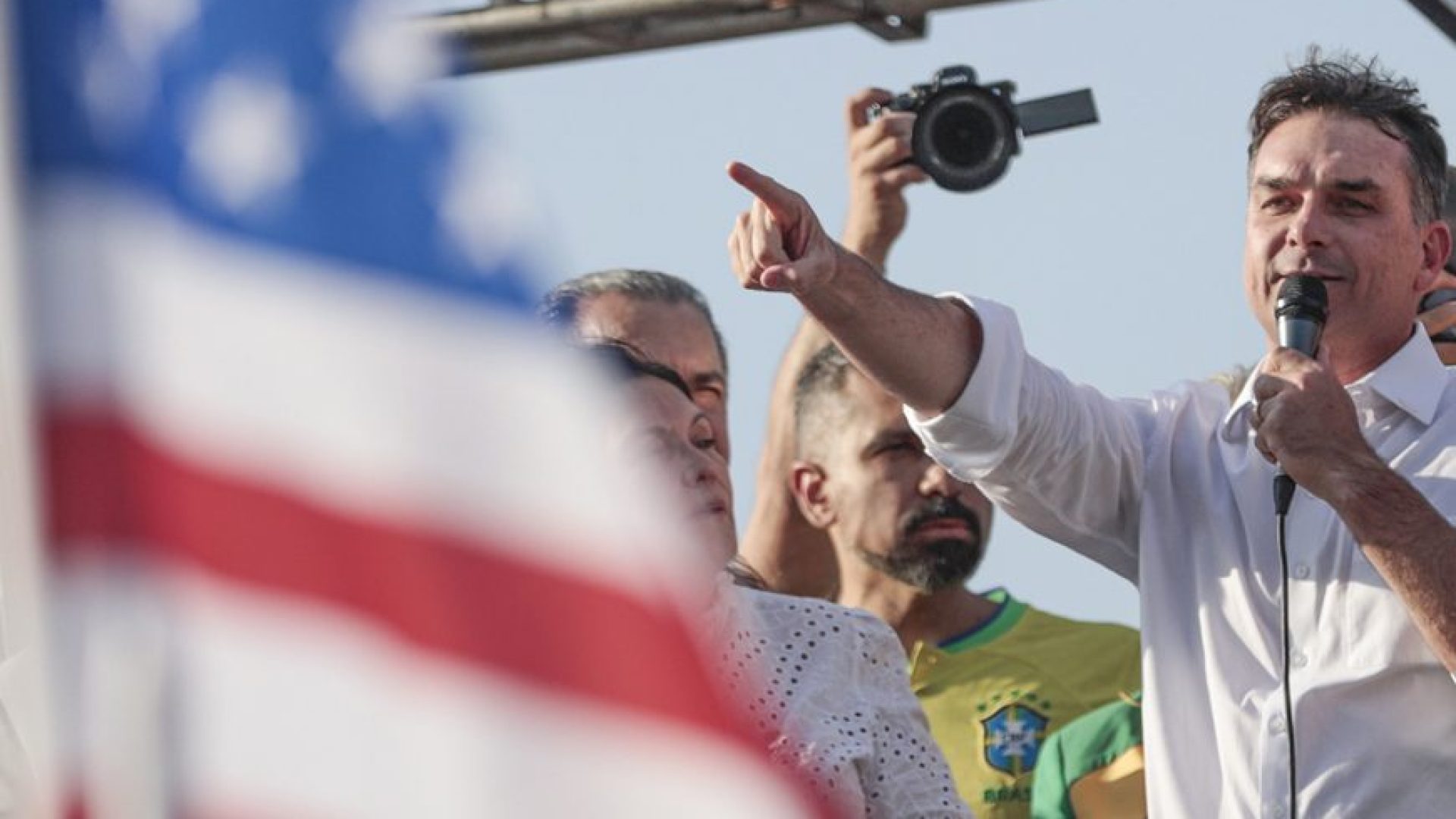 Flávio Bolsonaro em frente à bandeira americana (Foto: Joédson Alves - Agência Brasil)